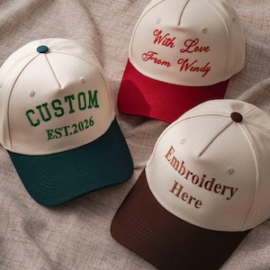 Puede incluir: Tres gorras de b&eacute;isbol con coronas color blanco hueso y viseras de colores. Una gorra tiene una visera verde oscuro y el texto CUSTOM EST.2026 en verde. Otra tiene una visera roja y el texto With Love From Wendy en rojo. La tercera tiene una visera marr&oacute;n y el texto Embroidery Here en marr&oacute;n.