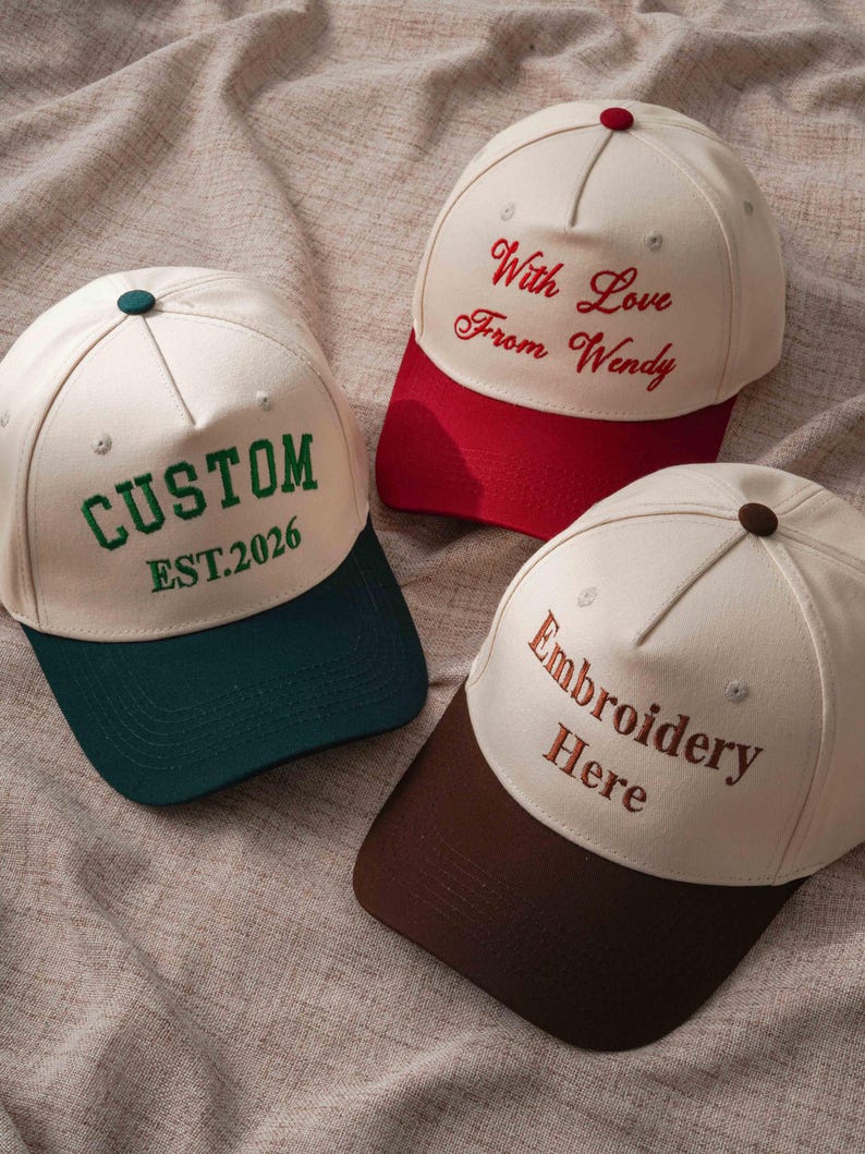 Puede incluir: Tres gorras de b&eacute;isbol con coronas color blanco hueso y viseras de colores. Una gorra tiene una visera verde oscuro y el texto CUSTOM EST.2026 en verde. Otra tiene una visera roja y el texto With Love From Wendy en rojo. La tercera tiene una visera marr&oacute;n y el texto Embroidery Here en marr&oacute;n.