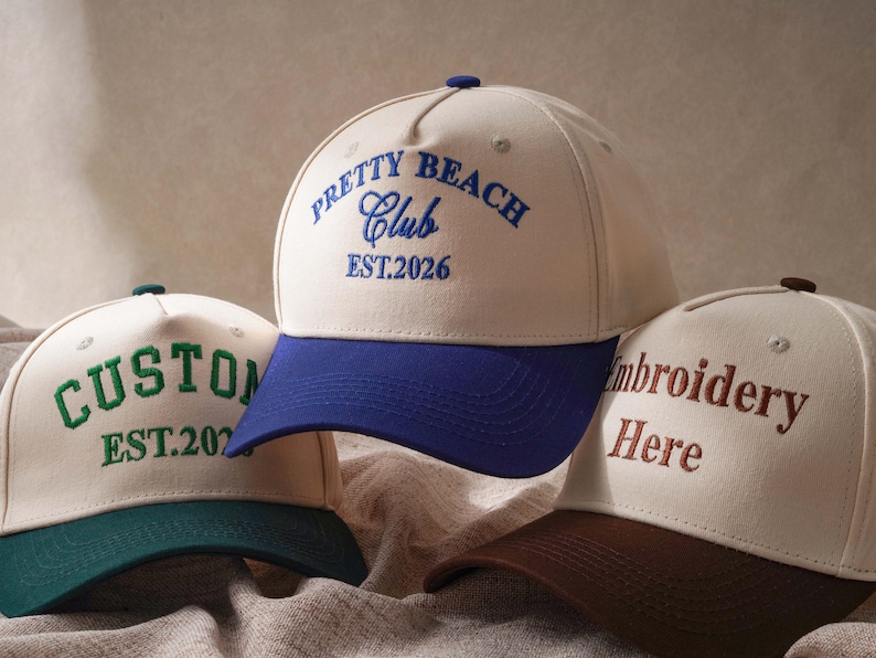 Puede incluir: Tres gorras de b&eacute;isbol con coronas de color crema y viseras en contraste. La gorra central tiene una visera azul y el texto azul PRETTY BEACH Club EST.2026. La gorra izquierda tiene una visera verde y el texto verde CUSTOM EST.2026. La gorra derecha tiene una visera marr&oacute;n y el texto marr&oacute;n Embroidery Here.