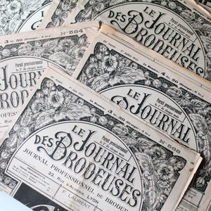 Puede incluir: Una colección de revistas francesas antiguas tituladas "Le Journal des Brodeuses" (El Diario de las Bordadoras). Las portadas en blanco y negro presentan diseños florales y texto. Las revistas están apiladas, algunas parcialmente visibles.
