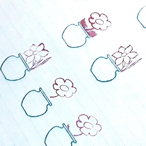 May include: A repeating pattern of hand-drawn flower pots with flowers. The pots are outlined in teal, and the flowers are in shades of red and purple. The background is a light blue lined paper.