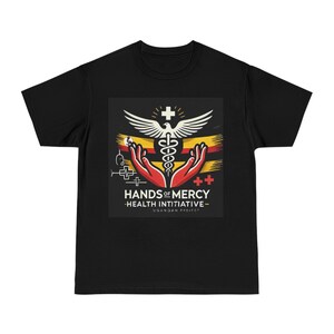 Op de afbeelding: Zwart T-shirt met een grafisch ontwerp. Het ontwerp bevat de tekst "HANDS OF MERCY - HEALTH INITIATIVE - UGANDAN PROJECT." De afbeelding toont een caduceussymbool, handen en een duif, met rode, gele en witte elementen.