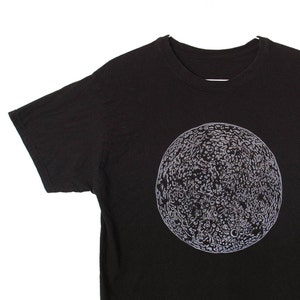 May include: A black t-shirt with a white graphic of the moon on the front.