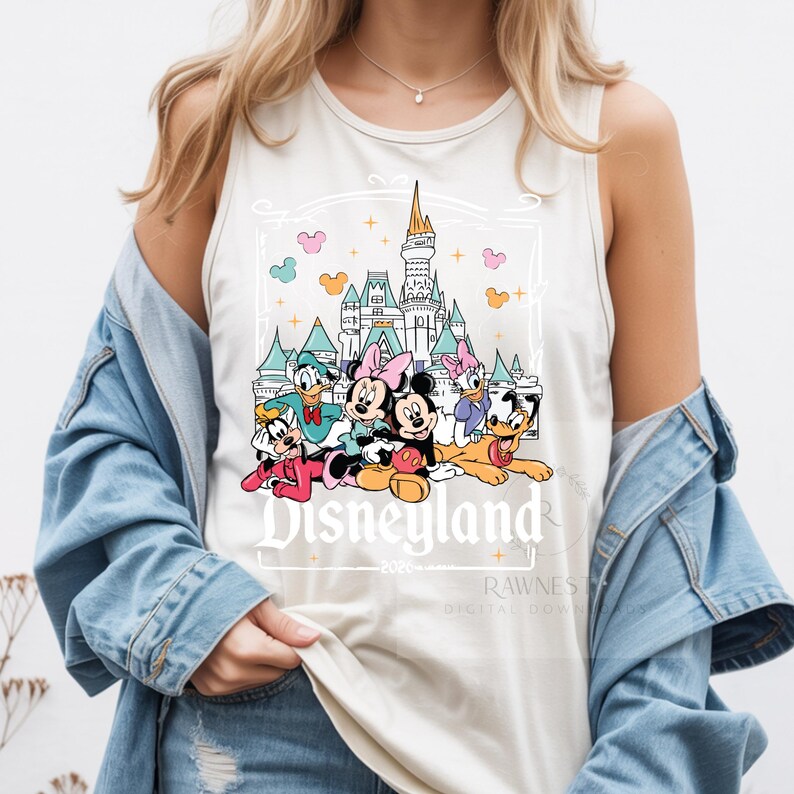 Peut inclure: Un d&eacute;bardeur sans manches de couleur cr&egrave;me avec une impression graphique de Mickey, Minnie, Donald, Daisy, Dingo et Pluto devant un ch&acirc;teau. Le texte Disneyland 2020 est imprim&eacute; sous les personnages dans une police de couleur blanche.