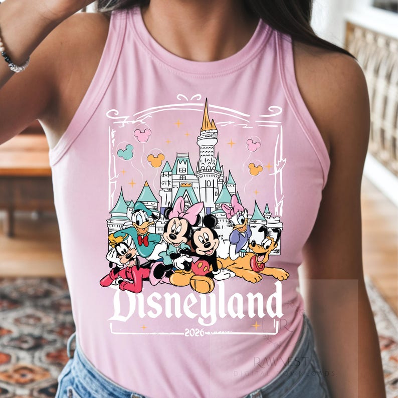 Peut inclure: Un d&eacute;bardeur rose clair sans manches avec une impression graphique repr&eacute;sentant un ch&acirc;teau, Mickey, Minnie, Donald, Daisy, Dingo et Pluto. Le texte Disneyland et 2026 est imprim&eacute; sous les personnages dans une police d&eacute;corative blanche.