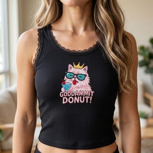 May include: Black ribbed vest top with a lace trim. The graphic on the front features a pink cat wearing sunglasses and a crown, holding a cocktail, with the text "GODDAMMIT DONUT!"