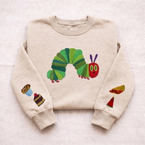 Puede incluir: Una taza de cerámica blanca con un asa negra y el texto "But First, Coffee" en un estilo manuscrito. La taza está sobre una superficie blanca. La taza mide aproximadamente 10 cm de alto.