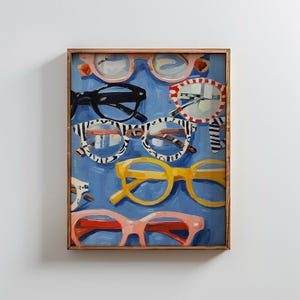 May include: A framed painting on a blue background featuring multiple pairs of eyeglasses in various styles and colors, including black, yellow, pink, and a white and black striped pattern, all arranged in a layered composition within a wooden frame.
