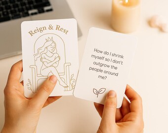 May include: Two cream-colored oracle cards are held in hands. One card has the text "Reign & Rest" and a line drawing of a woman. The other card has the text "How do I shrink myself so I don't outgrow the people around me?"