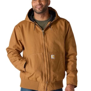 May include: A tan hooded jacket featuring a full-length front zipper, ribbed cuffs and hem, and two large front pockets. A small rectangular Carhartt brand label is stitched onto the lower left pocket. The interior lining is black.