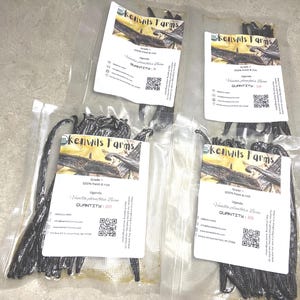 May include: Four vacuum-sealed bags of vanilla beans, each with a label from Kenvil's Farms. The labels state "Grade A 100% fresh & rich" and include the text "Uganda Vanilla planifolia Beans". The beans are dark brown.