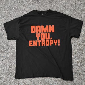 Puede incluir: Camiseta negra con el texto naranja "DAMN YOU, ENTROPY!". La camiseta tiene cuello redondo y está hecha de un material suave. El texto está en negrita, con una fuente sans-serif.