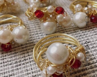 Anillo de alambre de oro con perlas y piedras preciosas rojas.