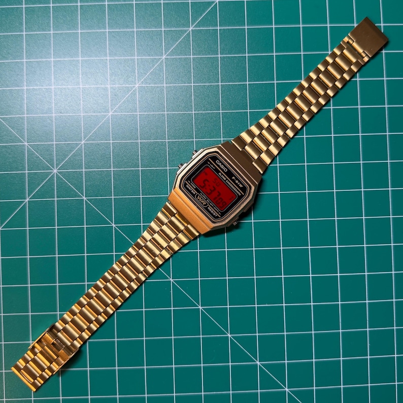 Peut inclure: Montre num&eacute;rique dor&eacute;e avec affichage rouge indiquant l'heure. Le bracelet est &eacute;galement dor&eacute;, avec un design &agrave; maillons classique. Le cadran affiche la marque "CASIO" et le mod&egrave;le "F-91W".