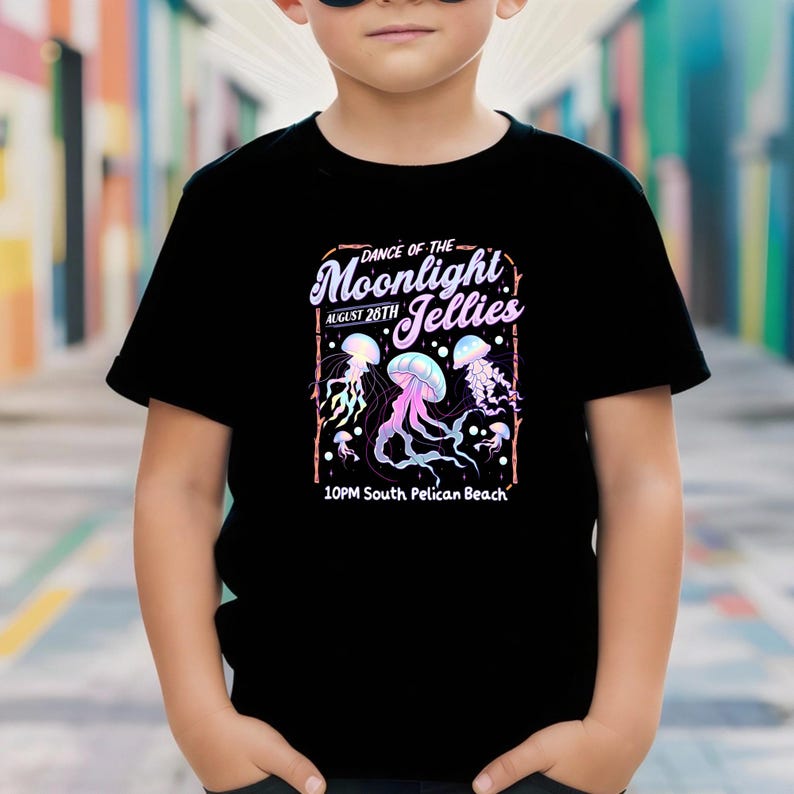 May include: Black t-shirt featuring a colorful graphic design. The design includes the text "Dance of the Moonlight Jellies" with the date "August 26th" and the location "10PM South Pelican Beach". The graphic also features jellyfish.