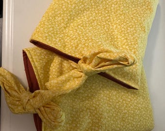 May include: Yellow floral fabric set with a matching bow. The fabric has a small white floral pattern on a yellow background. The set includes a rectangular piece and a bow.