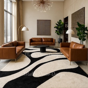 May include: A modern living room featuring three brown leather sofas with gold legs, a black coffee table, and a large black and white patterned rug. The room is illuminated by a starburst chandelier and two floor lamps.