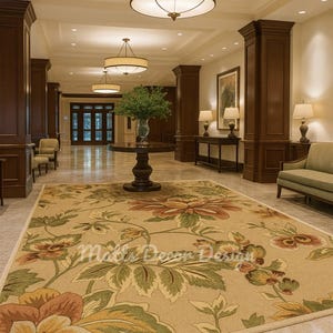 May include: An interior shot of a hotel lobby with a large floral rug in the foreground. The rug features large flowers in shades of orange, yellow, and green on a beige background. Overhead, there are several round light fixtures.
