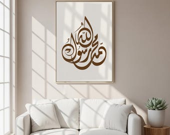 May include: A framed wall art print featuring elegant brown Arabic calligraphy on a cream background. The artwork is displayed in a gold frame, adding a touch of sophistication. The print is a decorative piece suitable for home decor.