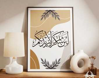 May include: Framed art print featuring Arabic calligraphy in black against a beige, white, and gray abstract background. The print includes leaf-like designs and is displayed on a wooden surface with a lamp and decorative vases.