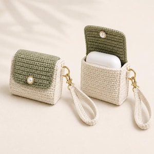 May include: Two crochet earbud cases featuring a cream-coloured body and an olive green flap. Each case includes a gold-toned metal clasp with a matching cream-coloured wrist strap and a small white faux pearl button closure on the front flap.