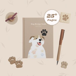 May include: A beige dog recipe book with a cartoon dog illustration, paw prints, and the text "Dog Recipe Book." Includes a wooden paw print stamp, pen, and paw print-shaped erasers. The book has over 25 pages.