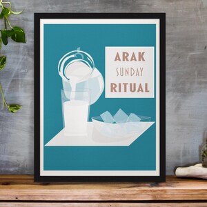May include: A framed art print featuring a teal background with a white shelf. The print depicts a pitcher pouring liquid into a glass, ice cubes in a bowl, and the text "ARAK SUNDAY RITUAL" in a rectangular box. The print is displayed on a wooden surface.