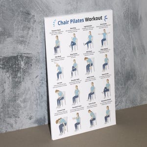 K&ouml;nnte beinhalten: Ein wei&szlig;es Poster mit dem Titel "Chair Pilates Workout" mit Illustrationen von &Uuml;bungen. Das Poster zeigt verschiedene &Uuml;bungen wie Haltungskontrolle, Marschieren und Armkreisen, mit Anweisungen und Diagrammen. Der Hintergrund ist eine strukturierte graue Wand.