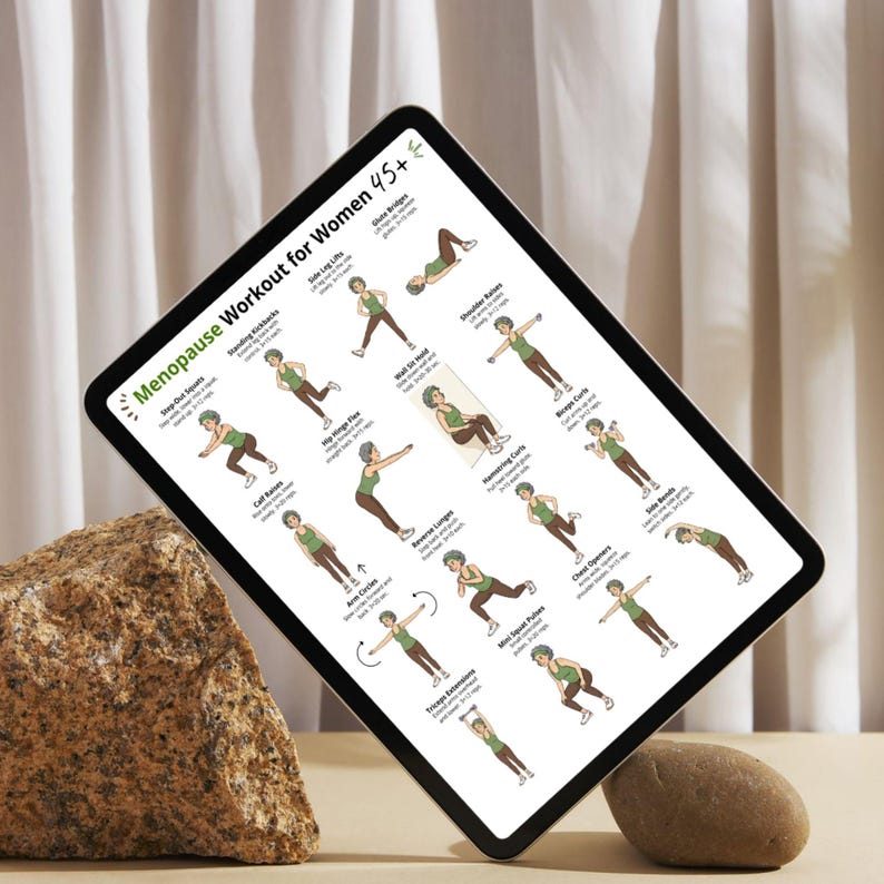Puede incluir: Una tableta digital muestra una rutina de ejercicios titulada "Menopause Workout for Women 45+". La pantalla muestra ejercicios ilustrados con instrucciones. La tableta est&aacute; apoyada por una roca grande y texturizada y una piedra peque&ntilde;a y lisa.