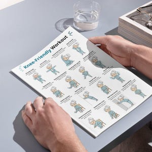 K&ouml;nnte beinhalten: Eine Person h&auml;lt ein gedrucktes Blatt mit dem Titel "Knee-Friendly Workout". Das Blatt zeigt illustrierte &Uuml;bungen, darunter Armkreisen, seitliches Dehnen im Sitzen und Nackendehnung. Die Illustrationen zeigen eine &auml;ltere Person, die die &Uuml;bungen ausf&uuml;hrt. Ein Glas Wasser ist sichtbar.