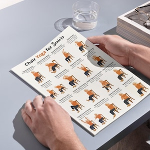 Puede incluir: Una persona sostiene una gu&iacute;a impresa titulada "Chair Yoga for Seniors". La gu&iacute;a presenta ilustraciones de varias posturas de yoga sentado, incluyendo estiramientos y ejercicios. La gu&iacute;a est&aacute; sobre una superficie gris con un vaso de agua y una pila de papeles.
