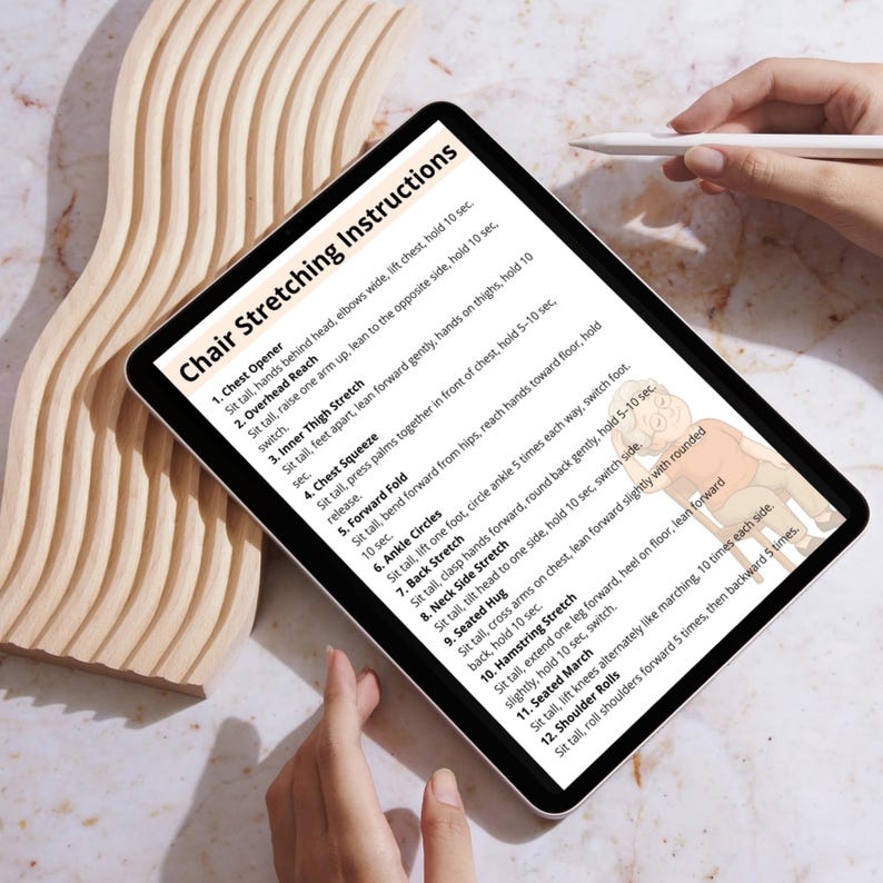 May include: A digital tablet displays "Chair Stretching Instructions" with a list of exercises. The tablet is held by a person, and a stylus is visible. The background features a light-colored wooden decorative element.
