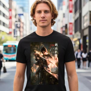 以下が含まれることがあります： 黒いTシャツ。武士の戦士が刀を持っている詳細なイラスト。グラフィックは、日本語のテキストが入った森の背景に設定されています。シャツは都市環境の人によって着用されています。
