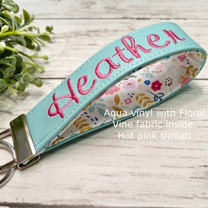 This keychain is looped to fit around your wrist for easy carrying. The outside is made of marine vinyl which is durable for every day use. Inside is fabric giving a soft feel against the skin. Size is about 5 inches long and 1.25 inches wide.