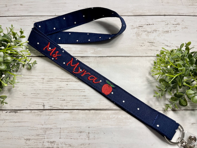 Teacher Name Lanyard for ID holder comes with embroidered apple. Fabric is navy dot. Neck strap for ID badge