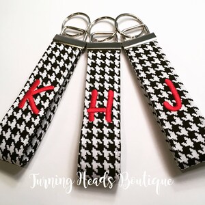 May include: Three black and white houndstooth keychains with red embroidered letters K, H, and J.