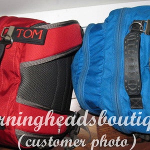 May include: Two blue and red backpacks with black straps and mesh panels. The backpacks have personalized name tags that read "TOM" and "WILL".