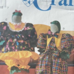 Pode incluir: Padrão de costura Simplicity Crafts com desenhos de bonecas palhaço. O padrão inclui instruções para fazer bonecas com roupas de tecido coloridas e estampadas. A capa exibe o logotipo Simplicity e o texto "Crafts".