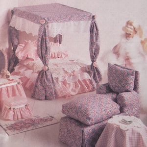 Puede incluir: Sobre de patrón de McCall's Crafts con un juego de dormitorio para casa de muñecas. El juego incluye una cama con dosel, un tocador, una silla y almohadas, todo en tela floral rosa. El texto "McCall's Crafts" está en la parte superior.