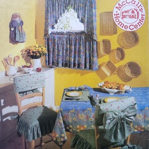May include: A McCall's Home Decorating pattern envelope. The cover shows a kitchen scene with floral tablecloths, curtains, and chair covers. The text "Kitchen Essentials" and "McCall's Home Decorating" are visible.
