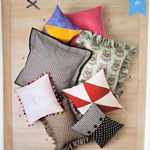 May include: A Kwik Sew K4294 sewing pattern envelope for pillows featuring various designs including a black and white geometric print, a cat print with ruffles, a white pillow with colorful pom-poms, and a red and white triangular pattern.