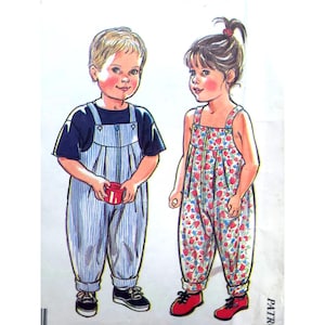 May include: A sewing pattern illustration featuring two children. One child wears a dark blue t-shirt under blue and white pinstriped overalls. The other child wears a floral print jumpsuit with red and blue flowers on a white background.