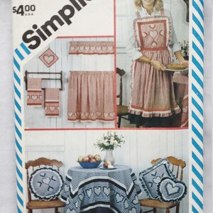 May include: Simplicity pattern envelope featuring a woman wearing a red and white gingham apron with heart accents. The image showcases coordinating kitchen textiles, including curtains, towels, and a tablecloth, all with heart designs. The envelope is labeled "6354".