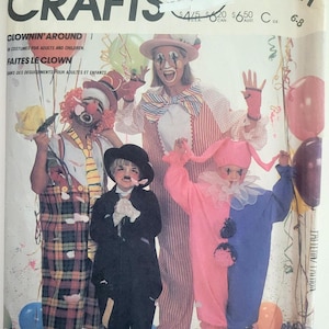 May include: A McCall's Crafts sewing pattern envelope 2211 for clown costumes. The cover features illustrations of four individuals in various clown outfits, including plaid overalls, a black suit, a striped shirt, and a pink and blue jumpsuit.