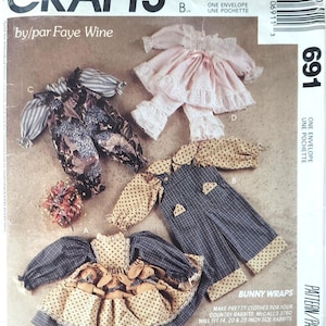 May include: McCall's Crafts pattern envelope showing bunny clothing designs. The cover displays various outfits, including a dress with bunny appliqués, overalls, and a pink ruffled ensemble. The text reads "Bunny Wraps" and "Make pretty clothes for your country rabbits."