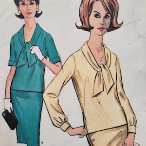 Può includere: Un'illustrazione vintage di un modello di cucito che mostra due donne con abiti abbinati. La donna a sinistra indossa un abito blu turchese con un fiocco e maniche corte. La donna a destra indossa un abito beige con un fiocco e maniche lunghe. Il modello è etichettato come "A Dressmaker Tested Design".