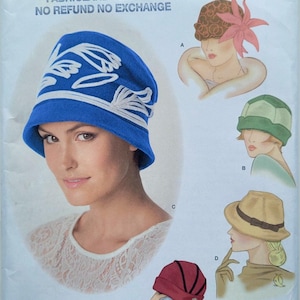 May include: Simplicity pattern 1736A features vintage hat designs. The cover showcases a woman wearing a blue cloche hat with white floral accents. Additional hat styles include a brown hat with a pink flower, a green hat, a tan hat, and a red hat.