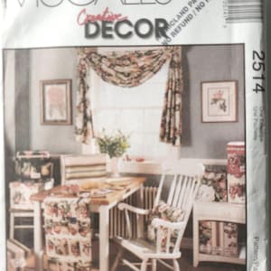 May include: A McCall's Creative Decor pattern envelope featuring a room setting with floral curtains, a table runner, and matching chair cushions. The image includes a white table, chair, and cabinet, with framed artwork on the wall.