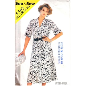 May include: A black and white printed dress with a collared neckline and a belt. The dress has a short sleeve and a knee-length skirt. The pattern is abstract and resembles musical notes. The dress is from a sewing pattern labelled "See & Sew 5562 Size C (20-22-24)".
