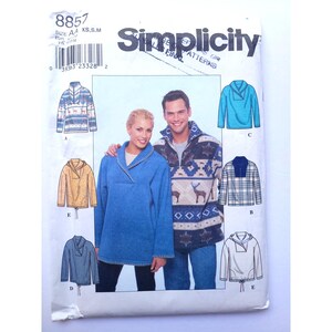 Puede incluir: Un sobre de patrón de costura Simplicity, número 8857, para tallas XS, S y M. El frente muestra ilustraciones y fotografías de varios tops tipo suéter con cuellos, capuchas y estampados, incluyendo un top azul sólido y uno con estampado de ciervos.